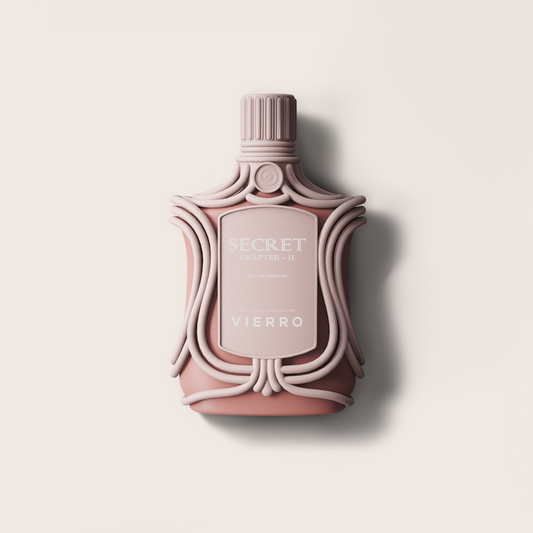 A sculptural perfume bottle in a dusty rose pink color with ornate details, featuring a ribbed cap and a central label that reads 'SECRET CHAPTER II' and 'VIERRO'. The bottle is centered against a warm off-white background with a soft shadow to the right.